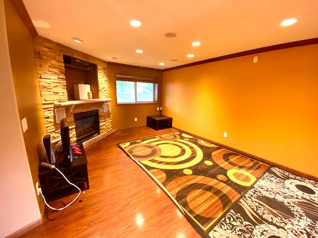 sitting room with crown molding, hardwood / wood-style flooring, and a stone fireplace