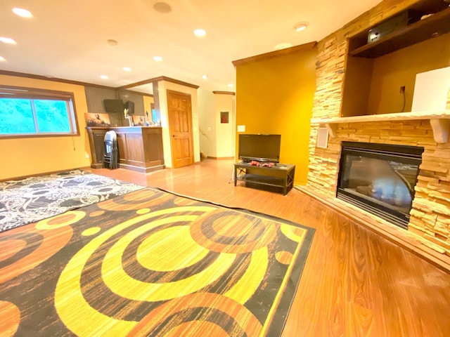 living room with ornamental molding, light hardwood / wood-style floors, and a stone fireplace