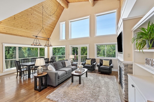 living room featuring an inviting chandelier, light hardwood / wood-style floors, beam ceiling, and a healthy amount of sunlight