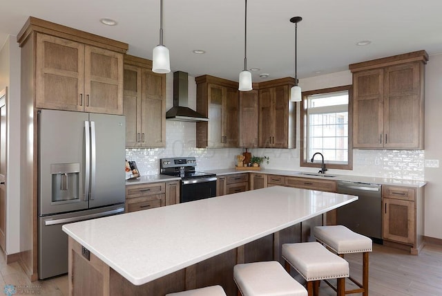 kitchen with a kitchen island, wall chimney exhaust hood, light hardwood / wood-style flooring, stainless steel appliances, and sink