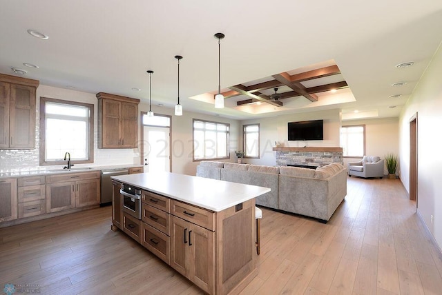 kitchen featuring appliances with stainless steel finishes, a sink, light countertops, a center island, and coffered ceiling