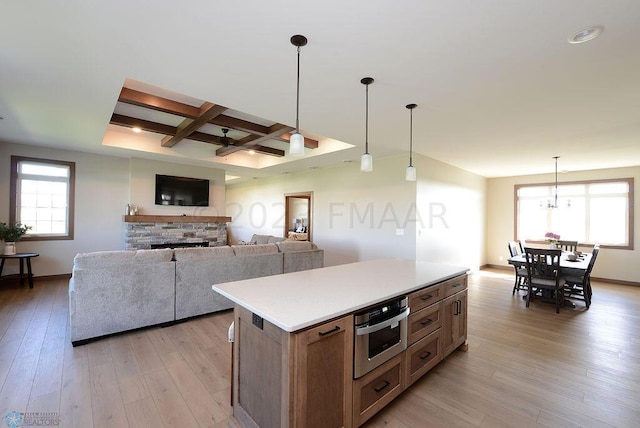 kitchen featuring light wood-style floors, stainless steel oven, a center island, light countertops, and coffered ceiling