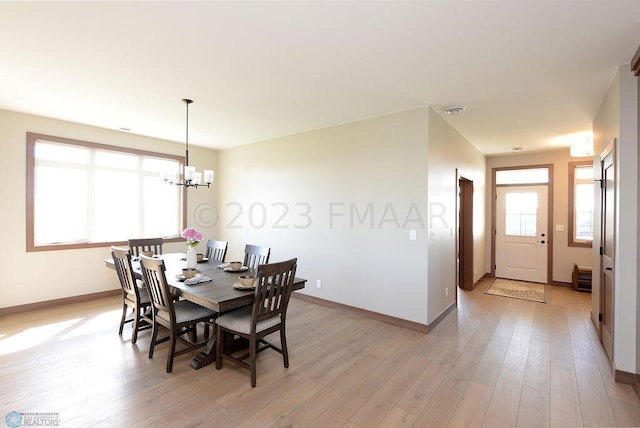 dining area featuring baseboards, light wood-style flooring, and a chandelier