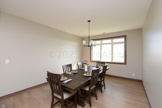 dining area with light hardwood / wood-style flooring and an inviting chandelier