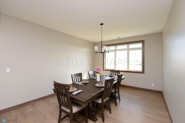 dining space featuring baseboards, a notable chandelier, and light wood-style floors