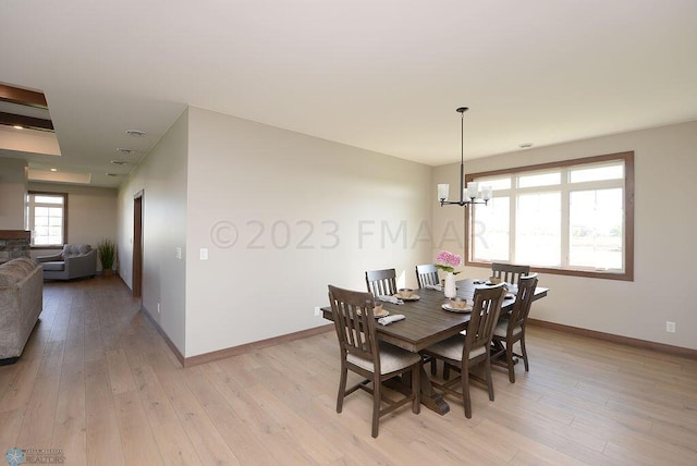 dining area featuring baseboards, light wood finished floors, and a chandelier