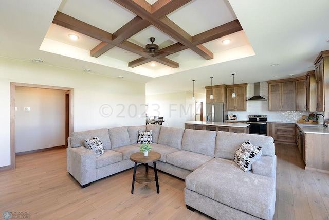 living area featuring a ceiling fan, beam ceiling, baseboards, coffered ceiling, and light wood-style flooring