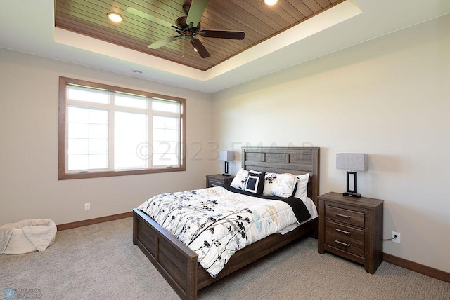 carpeted bedroom with a raised ceiling, ceiling fan, and wooden ceiling