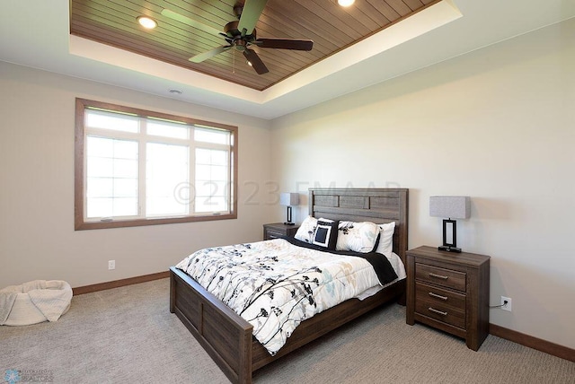 bedroom featuring wooden ceiling, baseboards, a tray ceiling, and light colored carpet