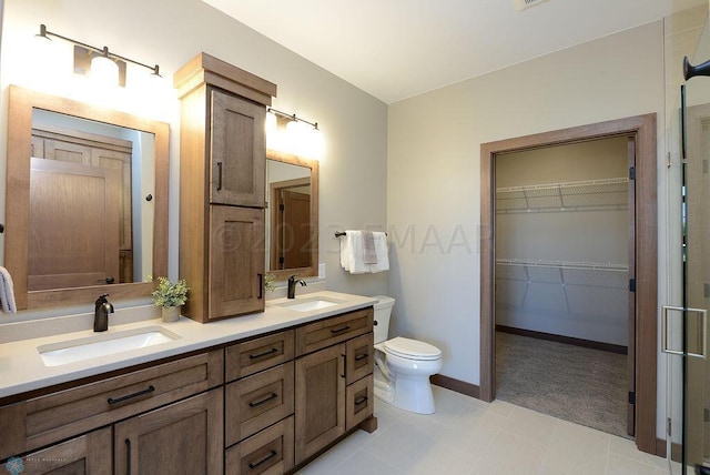 bathroom featuring a sink, baseboards, toilet, and double vanity