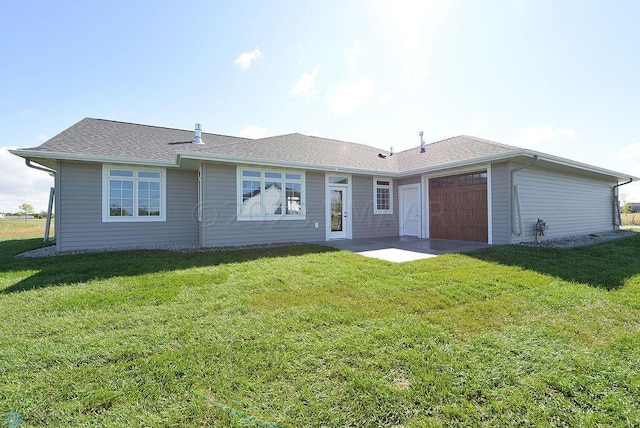 rear view of property with a yard and an attached garage