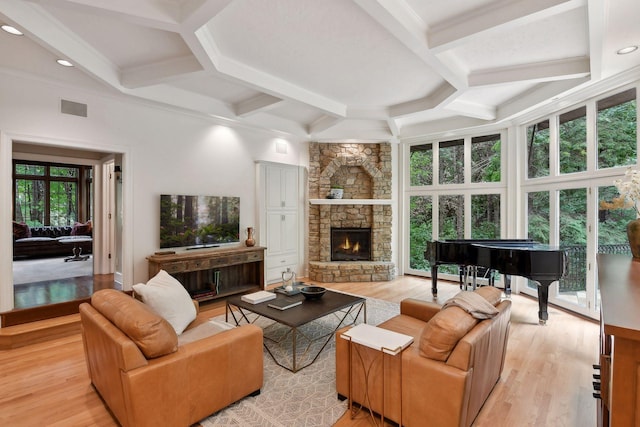 living room featuring beam ceiling, a stone fireplace, a healthy amount of sunlight, and light hardwood / wood-style floors