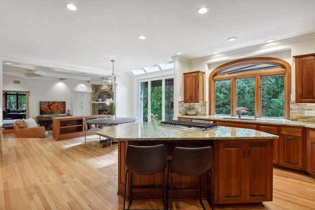 kitchen with decorative backsplash, a fireplace, light hardwood / wood-style floors, and decorative light fixtures