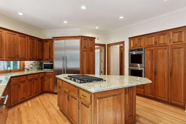 kitchen featuring light wood-type flooring, ornamental molding, and appliances with stainless steel finishes