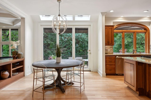 dining space with a healthy amount of sunlight, light wood-type flooring, ornamental molding, and an inviting chandelier