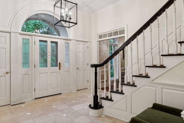 tiled entrance foyer featuring crown molding and a notable chandelier