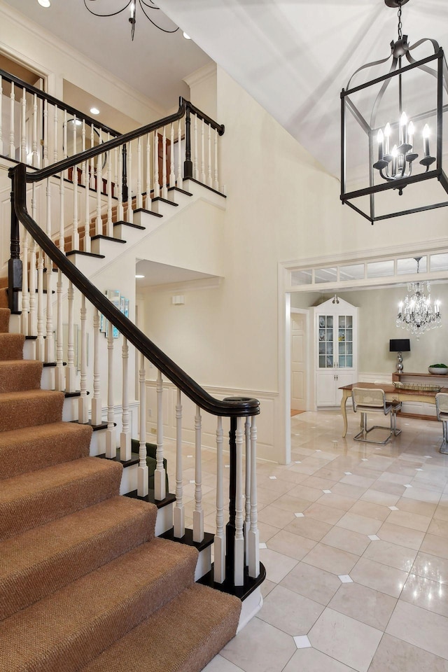 stairway with tile patterned flooring, a towering ceiling, and a chandelier