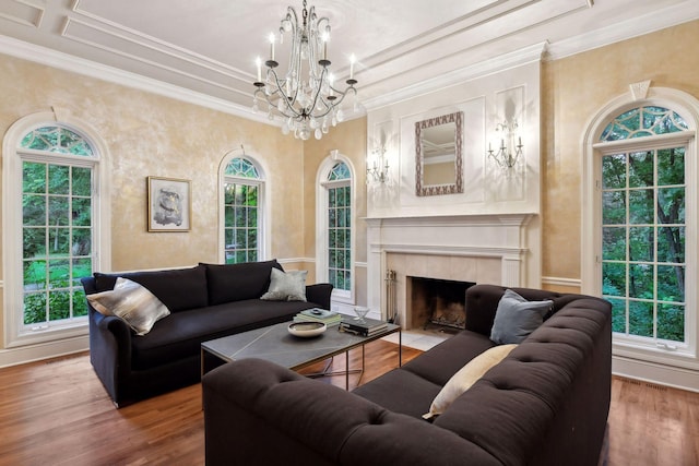 living room with a healthy amount of sunlight, wood-type flooring, ornamental molding, and a tile fireplace