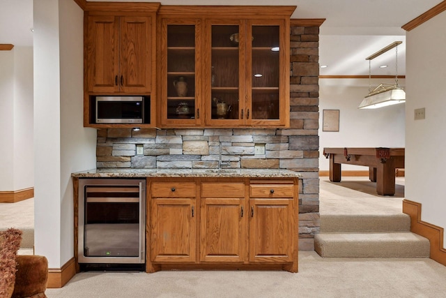 bar featuring light stone counters, crown molding, light carpet, and beverage cooler