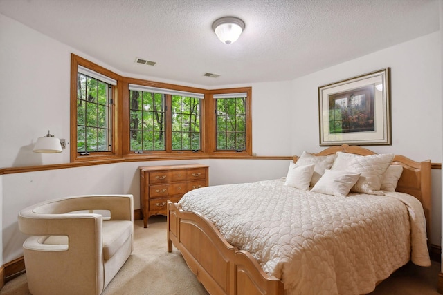 bedroom featuring light colored carpet and a textured ceiling