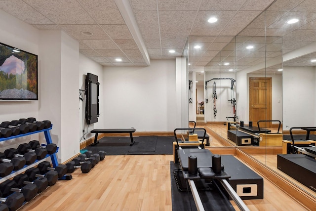 exercise room with wood-type flooring and a drop ceiling