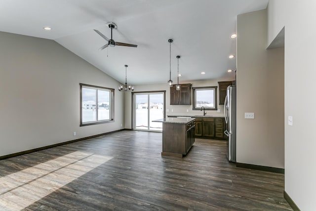 kitchen with dark hardwood / wood-style floors, sink, hanging light fixtures, a kitchen island, and stainless steel fridge