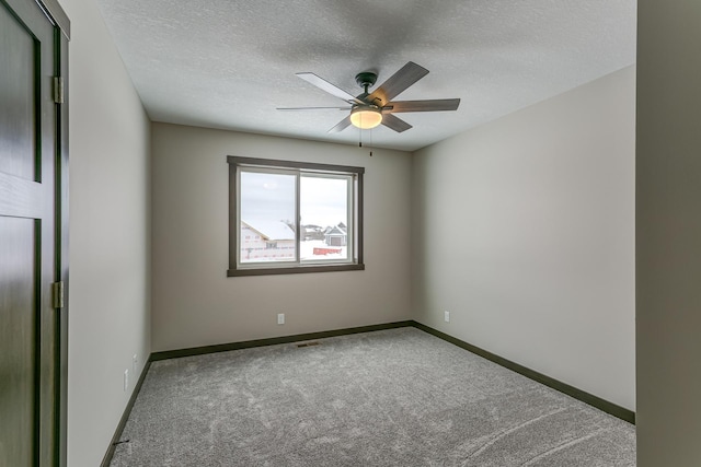 carpeted spare room with ceiling fan and a textured ceiling