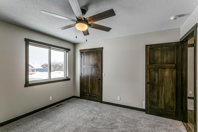 unfurnished bedroom with a textured ceiling, carpet, and ceiling fan