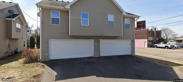 rear view of house featuring cooling unit and a garage