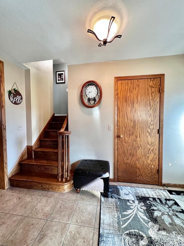 entryway featuring light tile patterned floors and a textured ceiling