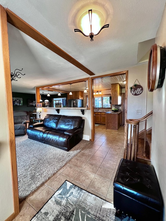 living room featuring sink, light tile patterned floors, and a textured ceiling