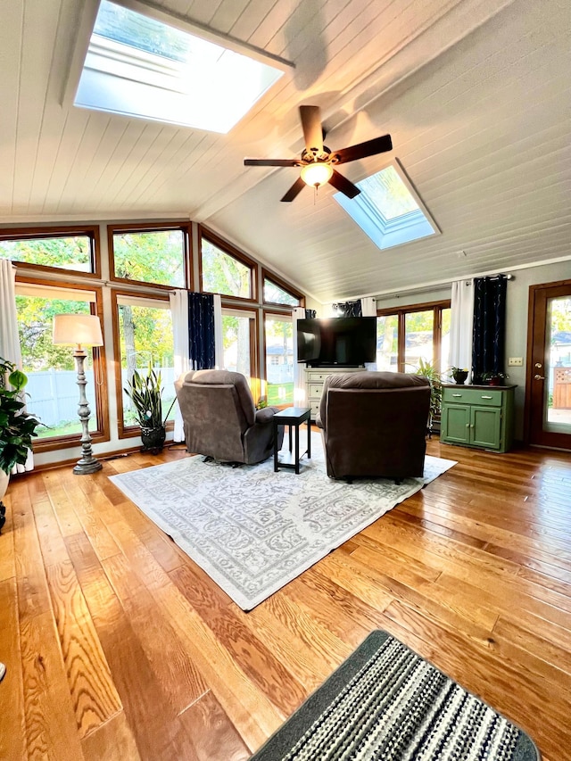 unfurnished living room with lofted ceiling with skylight, ceiling fan, and light wood-type flooring