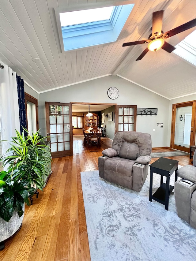 living room with ceiling fan, french doors, hardwood / wood-style floors, vaulted ceiling with skylight, and wood ceiling