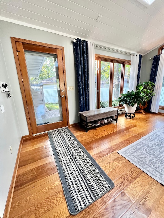 doorway with plenty of natural light, light hardwood / wood-style floors, and ornamental molding