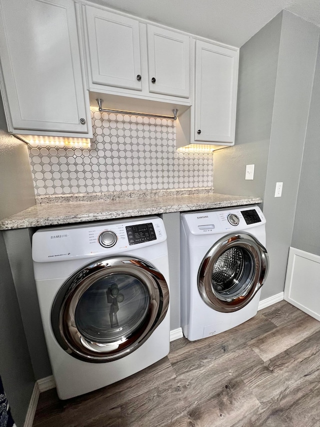 clothes washing area featuring dark hardwood / wood-style floors, cabinets, and independent washer and dryer