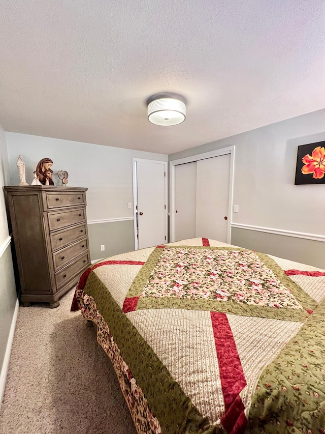 bedroom with a textured ceiling, light colored carpet, and a closet