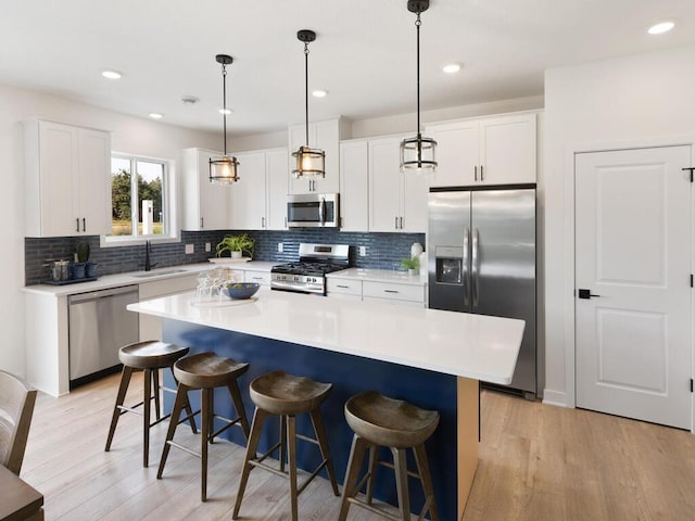 kitchen with white cabinetry, stainless steel appliances, a kitchen island, and hanging light fixtures