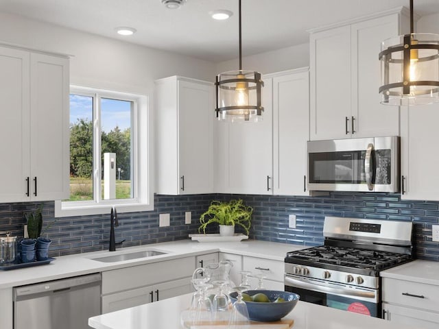 kitchen featuring backsplash, appliances with stainless steel finishes, white cabinetry, sink, and decorative light fixtures