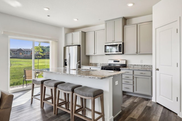 kitchen featuring appliances with stainless steel finishes, gray cabinets, sink, and a center island with sink