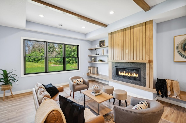 living room with beam ceiling, light hardwood / wood-style floors, and a fireplace