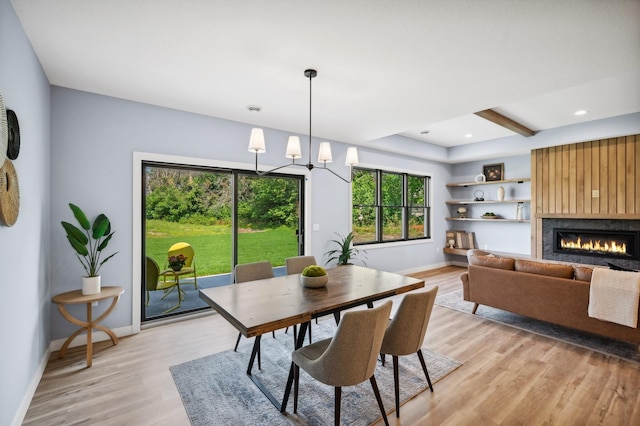 dining area featuring a fireplace, light hardwood / wood-style flooring, and an inviting chandelier