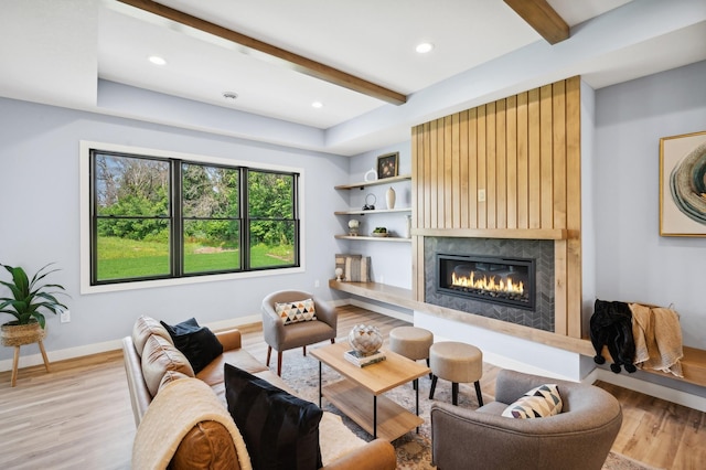 living area with wood finished floors, a fireplace, baseboards, and beamed ceiling