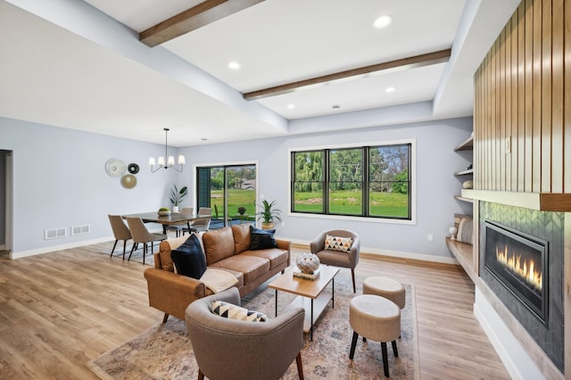 living room featuring light wood finished floors, visible vents, baseboards, beamed ceiling, and a large fireplace