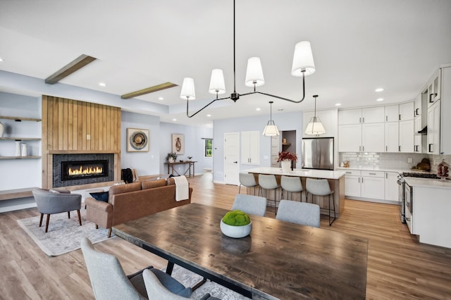 dining space with a fireplace, recessed lighting, and light wood-style floors