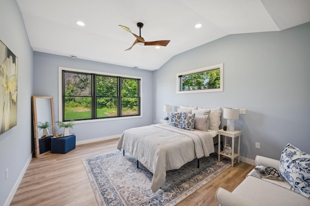 bedroom with lofted ceiling, wood finished floors, baseboards, and multiple windows