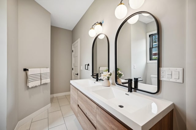 full bathroom with a sink, toilet, tile patterned flooring, double vanity, and baseboards