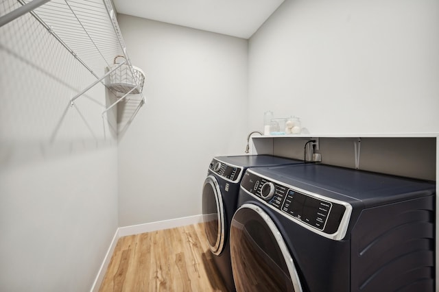 laundry room with light wood finished floors, laundry area, baseboards, and washing machine and clothes dryer