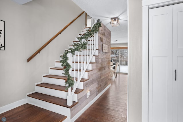 stairs with wood-type flooring and a textured ceiling