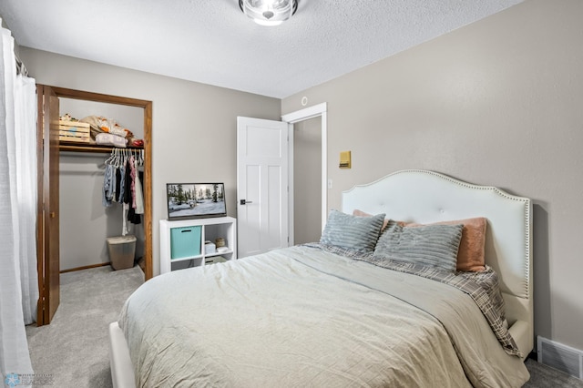 bedroom with carpet, a spacious closet, a textured ceiling, and a closet