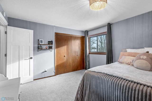 bedroom featuring a chandelier, a textured ceiling, carpet floors, and a closet